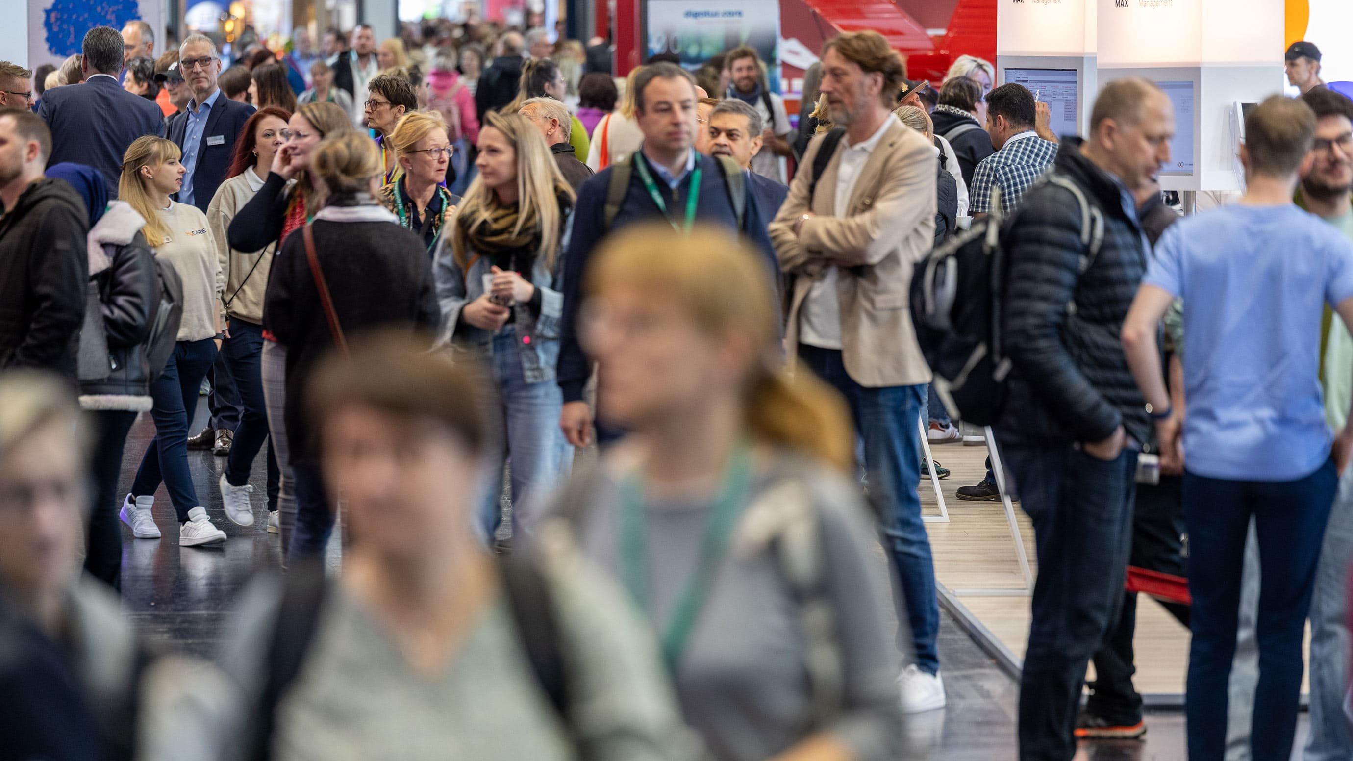 Besucher laufen durch die Messehalle